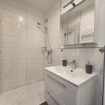 Badezimmer mit Dusche, Waschbecken und Spiegelschrank.