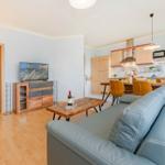 Wohnzimmer mit Sofa, TV und Küchenbereich mit Esstisch.