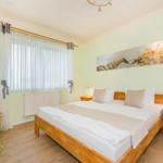 Ein Schlafzimmer mit Doppelbett, zwei Nachttischen und einem Fenster mit Vorhängen.