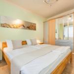 Schlafzimmer mit Doppelbett, Kleiderschrank und Wandbild.