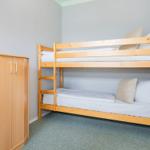 Zimmer mit Doppelstockbett und Holzschrank.