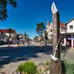 Zinnowitz Stadtmitte mit Markstein, Geschäften und Fußgängern an sonnigem Tag.