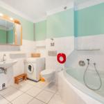 Badezimmer mit Badewanne, Waschmaschine und Spiegelkabinett.