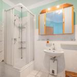Badezimmer mit Dusche, Waschbecken und Spiegelschrank.