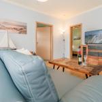 Wohnzimmer mit Sofa, Tisch, Fernseher und Blick in Schlafzimmer.