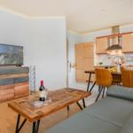 Wohnzimmer mit Küchenbereich, Couch, Tisch und TV.