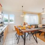 Küche mit Essbereich und Wohnzimmer mit Sofa und Holztisch.