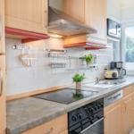 Küche mit Holzschränken, Herd, Spüle und Fenster mit Blick auf Grün.