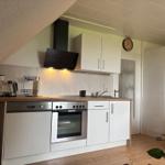 Küche mit weißen Schränken, Edelstahlgeräten und Holzoberfläche.