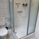 Badezimmer mit Dusche, Toilette und Fliesen