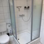 Badezimmer mit Dusche, Toilette und Fliesen