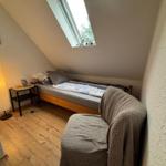 Dachgeschosszimmer mit Bett, Sessel und Dachfenster.