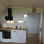 Küche mit Arbeitsplatte, Spüle, Herd und Dunstabzug.