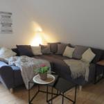 Ein Wohnzimmer mit Ecksofa, Beistelltischen und Pflanzen.