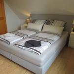 Schlafzimmer mit Doppelbett, Nachttischen und Holzboden.