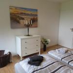 Zimmer mit Bett, Schrank, Bild und Blumen.