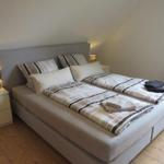 Doppelbett mit Bettwäsche, zwei Nachttische und Lampen.