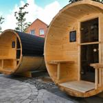 Zwei hölzerne Saunen mit Tür und Sitzbänken im Freien.