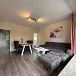 Wohnzimmer mit großer Sofaecke, Fernseher und Esstisch