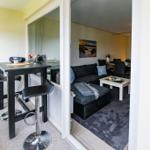 Barhocker und Tisch im Vordergrund. Wohnzimmer mit Sofa und Couchtisch im Hintergrund.