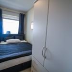 Schlafzimmer mit Bett, Gardinen und Kleiderschrank.