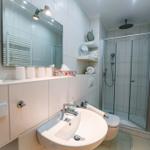 Badezimmer mit Dusche, Waschbecken und Heizkörper.