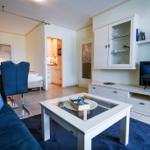 Wohnbereich mit Sofa, Couchtisch und TV. Küche und Schlafzimmer sind sichtbar.