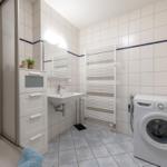 Badezimmer mit Waschmaschine, Handwaschbecken und Dusche.