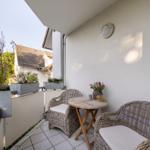 Terrasse mit zwei Stühlen, Tisch und Pflanzen. Blick auf Nachbarhaus.