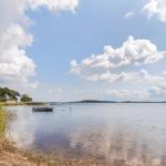Boot liegt am Ufer eines Sees unter blauem Himmel mit weißen Wolken.