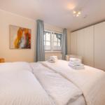 Schlafzimmer mit Doppelbett, Kleiderschrank und Fenster mit Vorhängen.