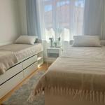 Zwei Betten mit hellen Bezügen und einem Nachttisch zwischen ihnen.