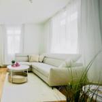 Wohnzimmer mit Ecksofa, weißem Tisch und Pflanzen.