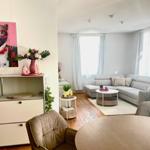 Wohnzimmer mit grauem Sofa, runden Tisch und Wandbild eines Leoparden.