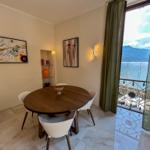 Dining room with table, chairs, and sea view from balcony.