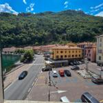 View of a square with parking, roads, and a lake in front of green hills.