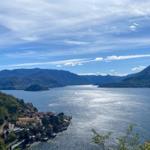 Panoramic view of a lake with mountains and a village along the shore.