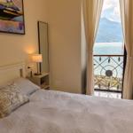 Bedroom with view of lake and mountains. Bed, nightstand, and window with curtains.