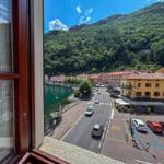 View of a lake and street with cars and green hills.