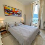 Bedroom with sea and mountain view. Bed, nightstands, wall art, and window.