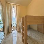 Room with bunk bed and balcony view of lake and mountains.