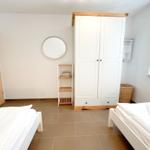 Zwei Betten, weißer Schrank und runder Spiegel im Zimmer.