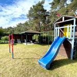 Hinterhof mit Spielhaus, Rutsche und Grillplatz unter Bäumen.