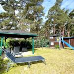 Grüner Garten mit Liegestühlen, Spielplatz und Pavillon unter Bäumen.