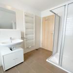 Badezimmer mit Dusche, Waschbecken und Heizkörper.