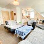 Wohn- und Essbereich mit Sofa, Sessel und Küchenbereich.