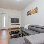 Wohnzimmer mit grauem Sofa, Fernseher und Wandbild.