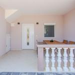 Terrasse mit Tisch, Stühlen und weißer Balustrade. Hintergrund: Tür und Fenster.