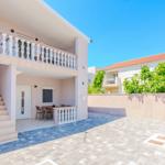 Haus mit Balkon, Terrasse und Treppe zur Eingangstür.