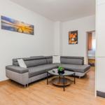 Wohnzimmer mit grauem Ecksofa, runden Tisch und Wandbildern.